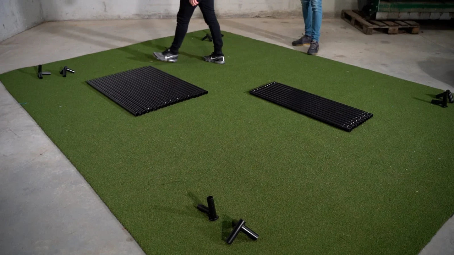 Green golf simulator mat with black frame components for indoor practice setup