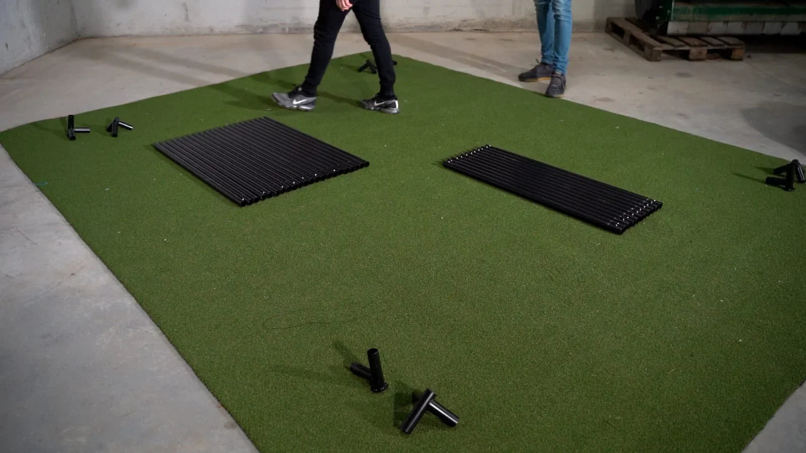 Green golf simulator mat with black frame components for indoor practice setup