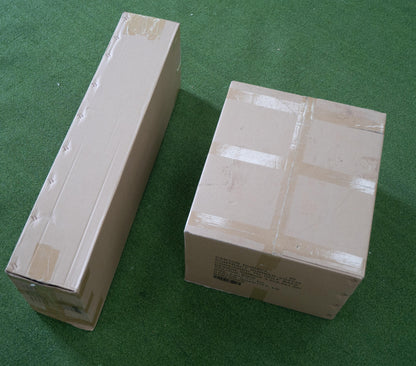 Two packaged golf simulator enclosures on green turf, ready for indoor golf setup