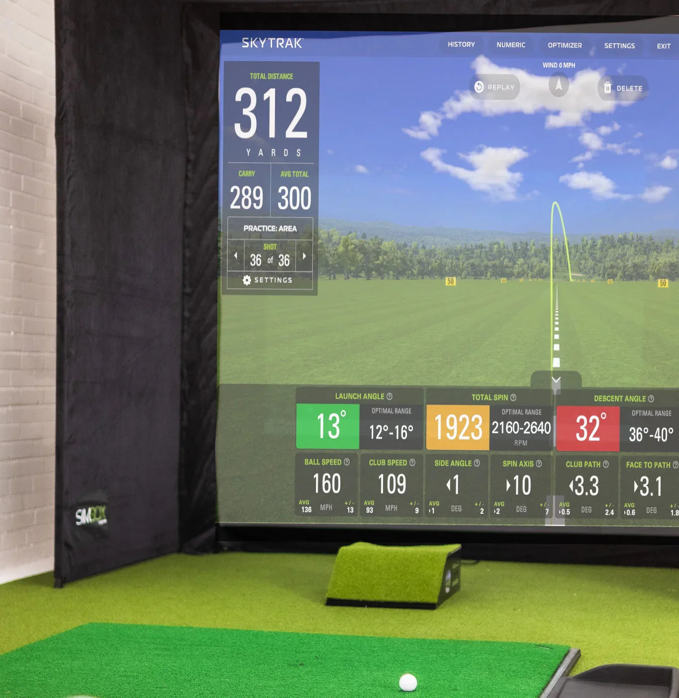 Indoor golf simulator with SkyTrak display, impact screen, and turf mat for home practice