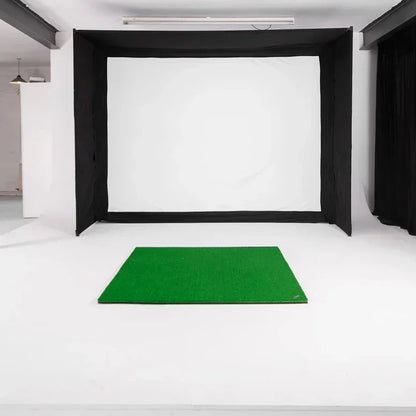Indoor golf simulator setup with green mat and impact screen enclosure for home practice