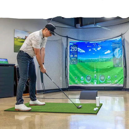 Man practicing golf swing on indoor simulator with SkyTrak display, impact screen, and turf mat for home or commercial use